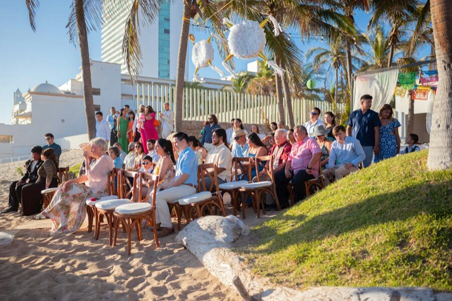 Guests seated on a beach at an outdoor ceremony